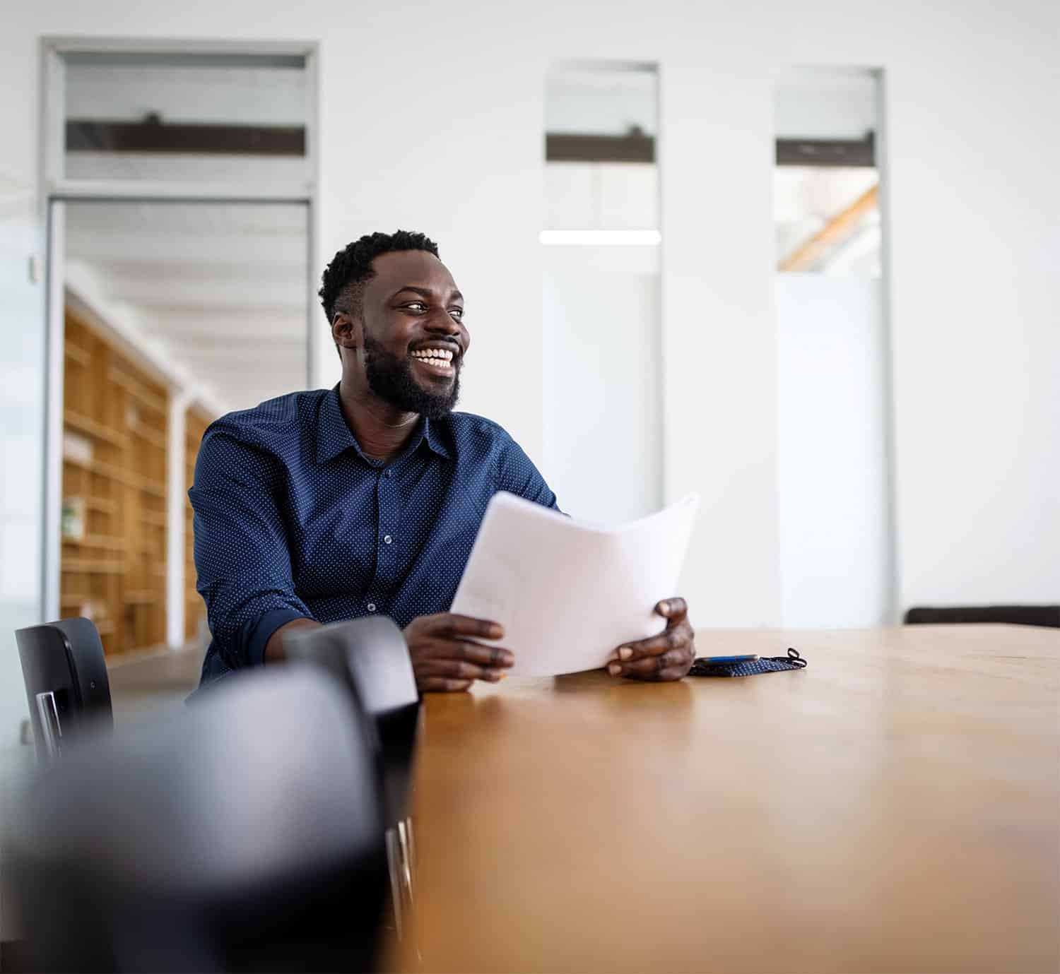 Happy-man-holding-papers-in-a-conference-room